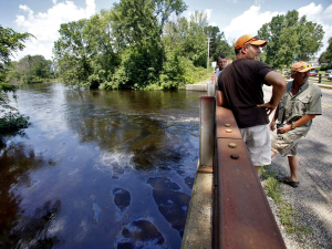 Déversement de pétrole dans la rivière Kalamazoo au Michigan, ÉU. En 2010. Le pétrole coüte de plus en plus cher, ça appauvrit et ça entraîne la détérioration des infrastructures par manque de fonds et négligence, et ça se perd de plus en plus en empoisonnant notre assise vitale : le top, l'eau, les plantes..